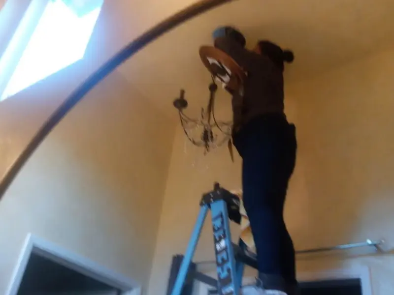 Electrician installing a chandelier in a Landis residence